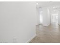Bright hallway featuring neutral tile flooring, fresh white paint and an open doorway at 35445 N Seedling St, San Tan Valley, AZ 85144