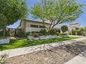 Beautifully landscaped home exterior with lush green trees, artificial turf, and stone planters at 4571 S Pinaleno W Dr, Chandler, AZ 85249