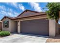 Beige single story home featuring an attached two-car garage, manicured landscaping, and a brown tiled roof at 5750 S 250Th Dr, Buckeye, AZ 85326