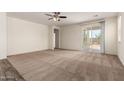 Spacious living room with plush carpeting, a ceiling fan, and sliding glass doors to the outdoor space at 5750 S 250Th Dr, Buckeye, AZ 85326