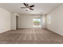 Bright and airy living room featuring neutral carpeting, a ceiling fan, and sliding glass doors at 5750 S 250Th Dr, Buckeye, AZ 85326