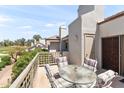 Relax on this private patio with a glass table and comfortable striped chairs, overlooking the community at 7272 E Gainey Ranch Rd # 48, Scottsdale, AZ 85258