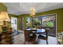 Dining room with olive green walls, large windows overlooking backyard, and decorative chandelier at 10591 E Saddlehorn Dr, Scottsdale, AZ 85258