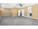Large main bedroom with neutral carpet, white trim, fan and open ensuite bathroom and walk in closet at 18640 W Pioneer St, Goodyear, AZ 85338