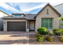 Inviting home exterior with a brick driveway, lush landscaping, and a two-car garage at 21127 W Minnezona Ave, Buckeye, AZ 85396