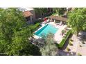 A birds eye view of a refreshing community pool with umbrella covered table, and shaded lounge chairs at 8260 E Arabian Trl # 257, Scottsdale, AZ 85258