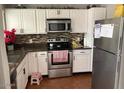 Well-lit kitchen featuring white cabinets, granite countertops, and stainless steel appliances at 849 W Duke Dr, Tempe, AZ 85283
