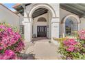 Inviting home entrance with an arched doorway, black double doors, and colorful bougainvillea at 9736 E Turquoise Ave, Scottsdale, AZ 85258
