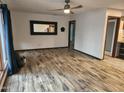 Open living room with wood floors, ceiling fan, large mirror, and view into the kitchen area at 12607 N 23Rd St, Phoenix, AZ 85022