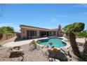 Beautiful backyard featuring a freeform pool, covered patio, and desert landscaping at 13458 W Coronado Rd, Goodyear, AZ 85395