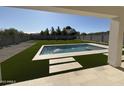 A luxurious backyard oasis featuring a sparkling pool with water features, artificial grass, and ample patio space at 26655 S 169Th Pl, Queen Creek, AZ 85142
