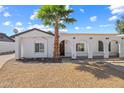 Charming single-story home with desert landscaping, white stucco, arched porch and mature palm tree at 5127 W Willow Ave, Glendale, AZ 85304