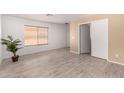 Spacious bedroom with wood-look tile flooring, neutral walls, and a window for natural light at 12132 W Dahlia Dr, El Mirage, AZ 85335