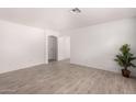 Bright living room featuring wood-look tile flooring, neutral walls, and an arched doorway at 12132 W Dahlia Dr, El Mirage, AZ 85335