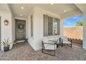 Inviting covered porch with comfortable seating, a stylish front door with wreath, and brick-paved flooring at 1876 S Huish Dr, Gilbert, AZ 85295