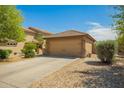 Beige two-car garage with desert landscaping, tile roof, and a spacious driveway at 22191 W Tonto St, Buckeye, AZ 85326