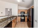 Bright kitchen features neutral cabinetry, granite counters and black appliances at 2433 W Hayden Peak Dr, San Tan Valley, AZ 85144