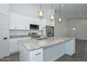 Modern kitchen with stainless steel appliances, stone countertops, a center island, and pendant lighting at 32017 N Redding St, Wittmann, AZ 85361