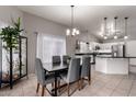 Open concept dining room with gray upholstered chairs, tile flooring and modern light fixture at 4109 E Chambers St, Phoenix, AZ 85040