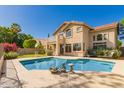 Outdoor pool area with a spacious patio and a two-story home with a balcony in the background at 5953 W Aurora Dr, Glendale, AZ 85308