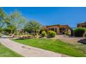 Charming home featuring a well-manicured lawn, colorful shrubbery, and an inviting front patio, all under a clear blue sky at 650 E Myrtle Pass, Queen Creek, AZ 85140