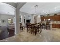 This open concept dining room displays travertine floors and an elegant light fixture at 6694 S Banning St, Gilbert, AZ 85298