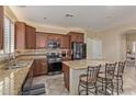 This kitchen features a granite island with seating, stainless steel appliances, and dark wood cabinets at 81 E Rock Wren Dr, San Tan Valley, AZ 85143