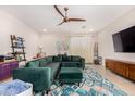 Spacious living room featuring modern decor, a ceiling fan, and an inviting emerald green sectional at 19875 W Badgett Ln, Litchfield Park, AZ 85340