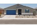 Charming single-story house boasts a blue garage door and desert-style front yard landscaping at 37151 W Parador Ln, Maricopa, AZ 85138