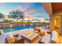 Beautiful backyard with a pool, fire pit, travertine tile, and comfortable seating at sunset at 12428 S 179Th Ln, Goodyear, AZ 85338