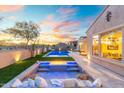 Inviting backyard with a sparkling pool, fire pit, and comfortable seating area under a beautiful sunset sky at 12428 S 179Th Ln, Goodyear, AZ 85338
