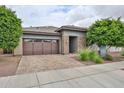 Beautiful single-story home featuring brick accents, lush landscaping, and a paved driveway at 16140 W Sierra St, Surprise, AZ 85379