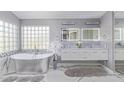 Bright bathroom with a soaking tub, marble floors, double vanity with a marble countertop, and a decorative accent wall at 7162 W Lone Cactus Dr, Glendale, AZ 85308