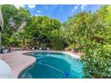 Backyard pool surrounded by lush landscaping and rock features, offering a serene outdoor retreat at 7162 W Lone Cactus Dr, Glendale, AZ 85308