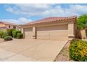 Spacious three-car garage featuring tan doors, accompanied by well-manicured landscaping and a tile roof at 9154 E Caribbean Ln, Scottsdale, AZ 85260
