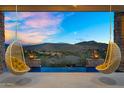 Breathtaking sunset view from the patio featuring a pool and swinging chairs with desert landscape at 13209 N 17Th Pl, Phoenix, AZ 85022