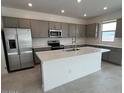 Modern kitchen with stainless steel appliances, gray cabinetry, and a large white center island at 25151 W Wayland Dr, Buckeye, AZ 85326