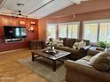 Warm living room with large TV, brown sofas, wood flooring and a square coffee table on an area rug at 2763 N Wright Way, Mesa, AZ 85215