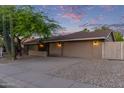Single-story home with desert landscaping, a two-car garage, and warm exterior lighting at 5008 E Nisbet Rd, Scottsdale, AZ 85254
