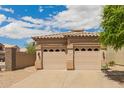 A well-maintained two-car garage with decorative windows and a stucco exterior under a bright, cloudy sky at 10652 W Coronado Rd, Avondale, AZ 85392