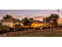 Charming single-story home with lush landscaping and warm exterior lighting at sunset at 14749 E Pecos Rd, Gilbert, AZ 85295
