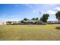 Expansive front yard view of a single story home, American flag, and well-maintained lawn at 14749 E Pecos Rd, Gilbert, AZ 85295