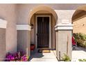 Close-up of the front door, showcasing the arched entryway, secure screen door, and charming welcome mat at 18484 W Westfall Way, Surprise, AZ 85374