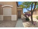 Inviting home entrance with a wooden door, desert landscaping, and mature trees at 204 S Valle Verde --, Mesa, AZ 85208