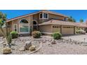 Charming two-story home featuring a clay tile roof, an attached two car garage, and desert landscaping at 8911 E Sutton Dr, Scottsdale, AZ 85260