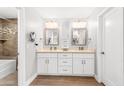 Bathroom features a double sink vanity, decorative mirrors, and a tub and shower combo with decorative tile at 1744 E Huber St, Mesa, AZ 85203