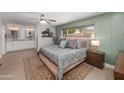 Comfortable main bedroom with a ceiling fan, ensuite bathroom with double sinks, and a view of the front yard at 1744 E Huber St, Mesa, AZ 85203