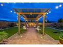 Outdoor living space with a pergola, string lights, lush landscaping, and comfortable seating at 18722 W Denton Ave, Litchfield Park, AZ 85340