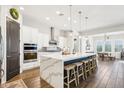 Modern kitchen features a large waterfall island with seating, stainless steel appliances, and stylish pendant lighting at 22848 N 98Th Dr, Peoria, AZ 85383