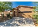 A one-story tan home with a red-tiled roof, a two-car garage, and mature landscaping at 44188 W Cydnee Dr, Maricopa, AZ 85138